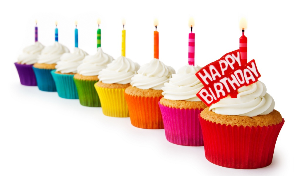 Кексы со свечами и кремом на день рождения на белом фоне 