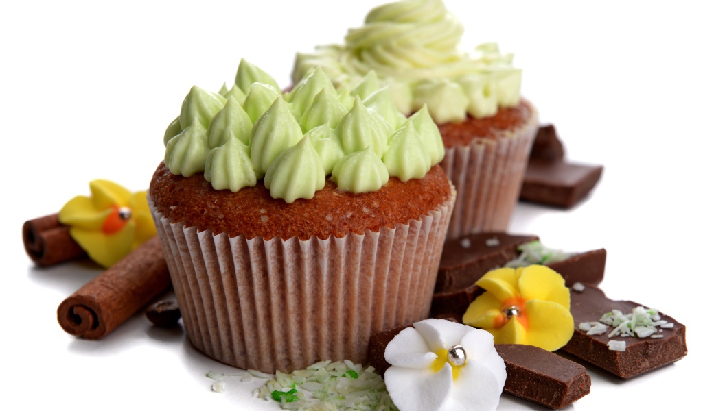 Кексы с кремом, шоколадом и корицей на белом фоне