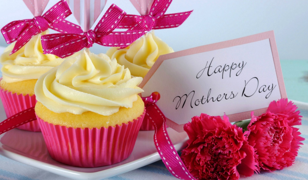 Кексы с кремом рядом с гвоздиками и пожеланиями к Дню матери