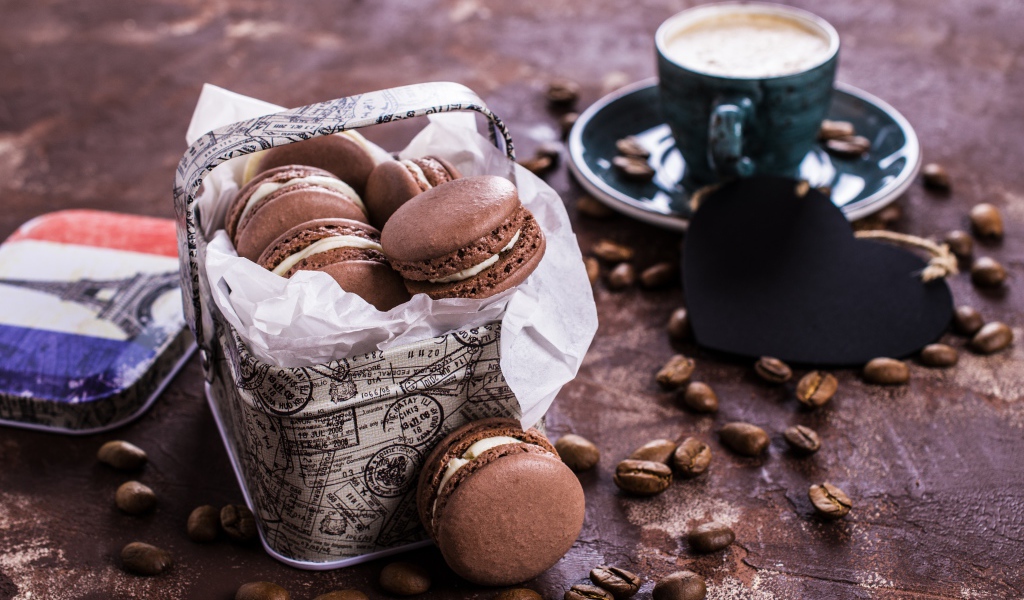 Десерт макарон на столе с кофейными зернами и чашкой кофе