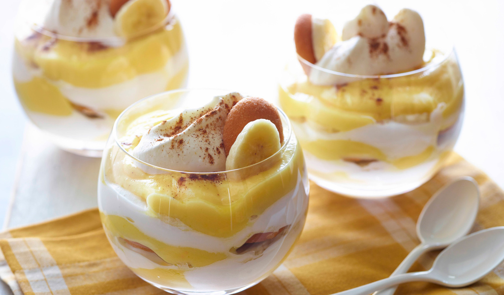 Десерт с бананами и печеньем в стаканах на столе 