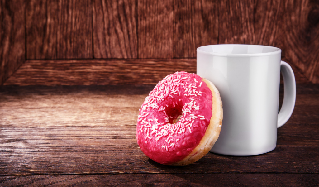 Пончик с белой кружкой на деревянном столе