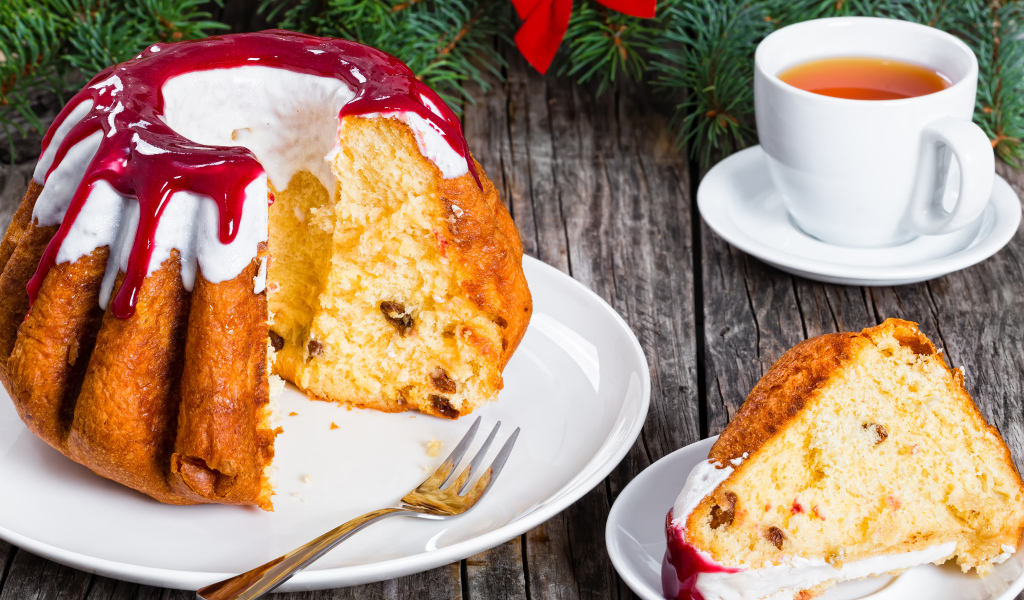 Праздничный кекс с глазурью на столе с чашкой чая