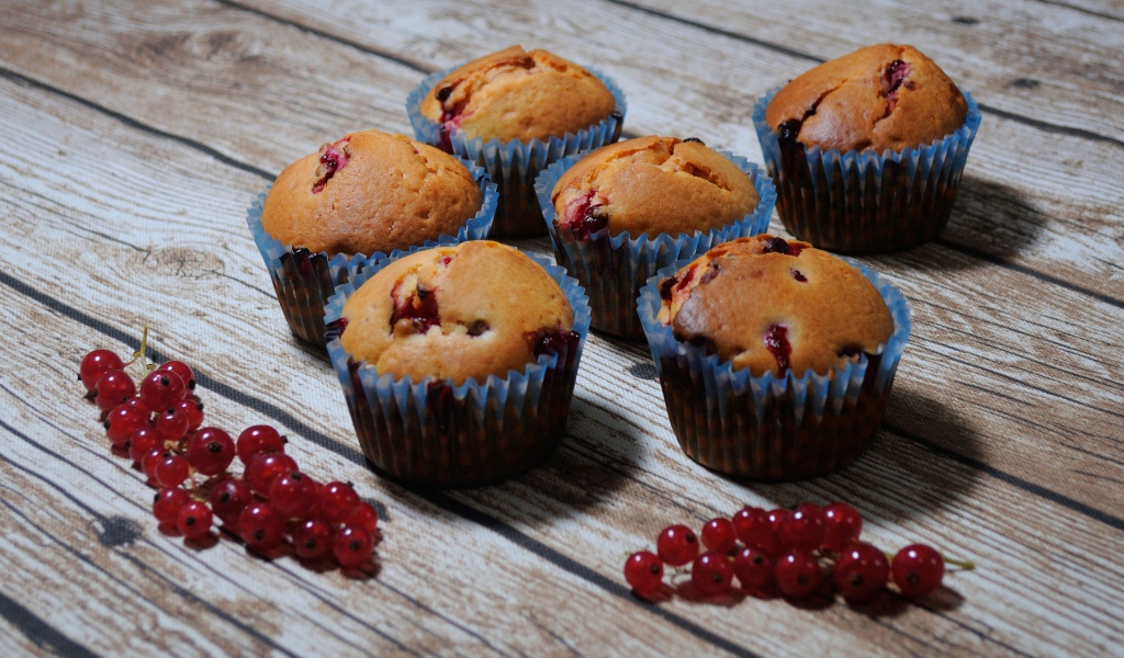 Свежие кексы с красной смородиной на деревянном столе 