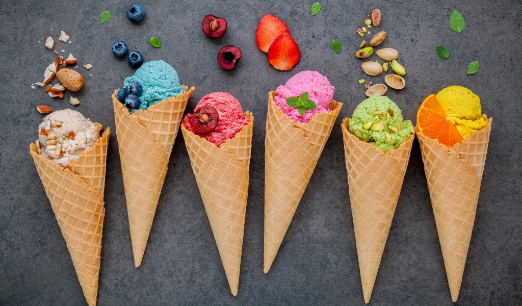 Шарики фруктового мороженого в вафельных рожках на сером фоне