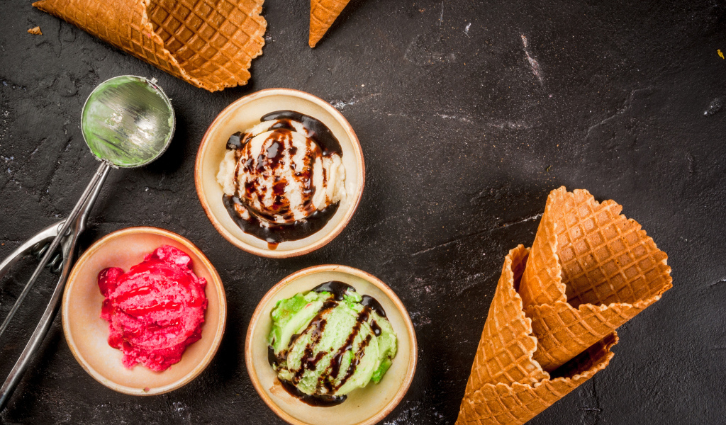 Шарики мороженого с вафельными рожками на столе 