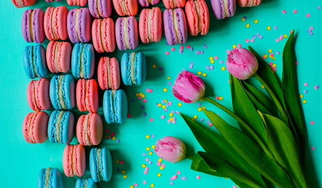 Разноцветные десерты макарун на столе с тюльпанами