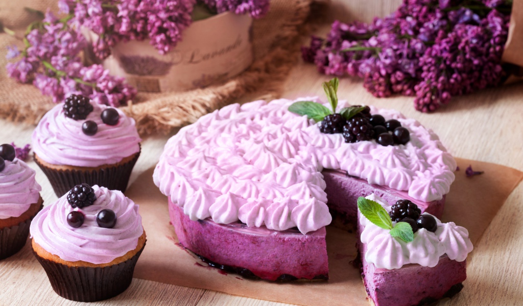 Пирог с кремом и вкусными кексами с черникой на столе с цветами сирени