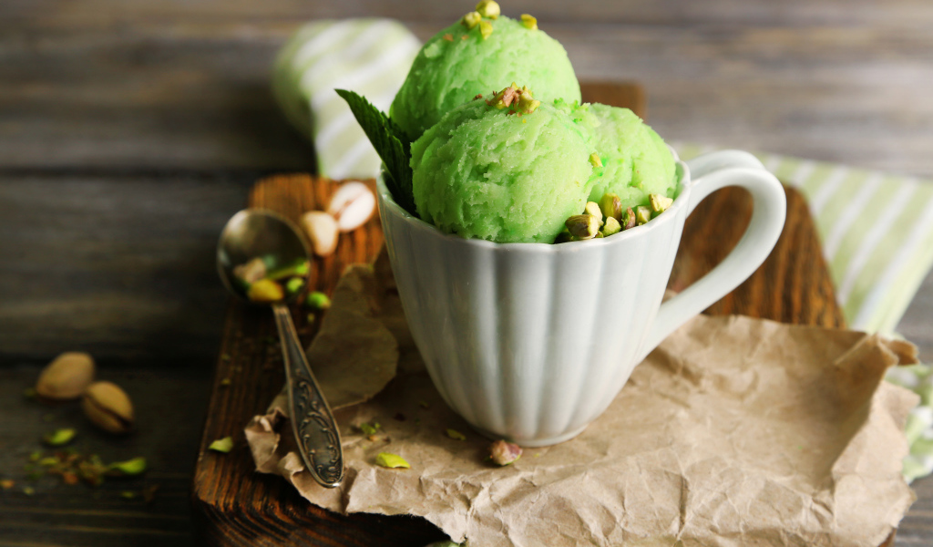 Фисташковое мороженое в белой чашке на столе