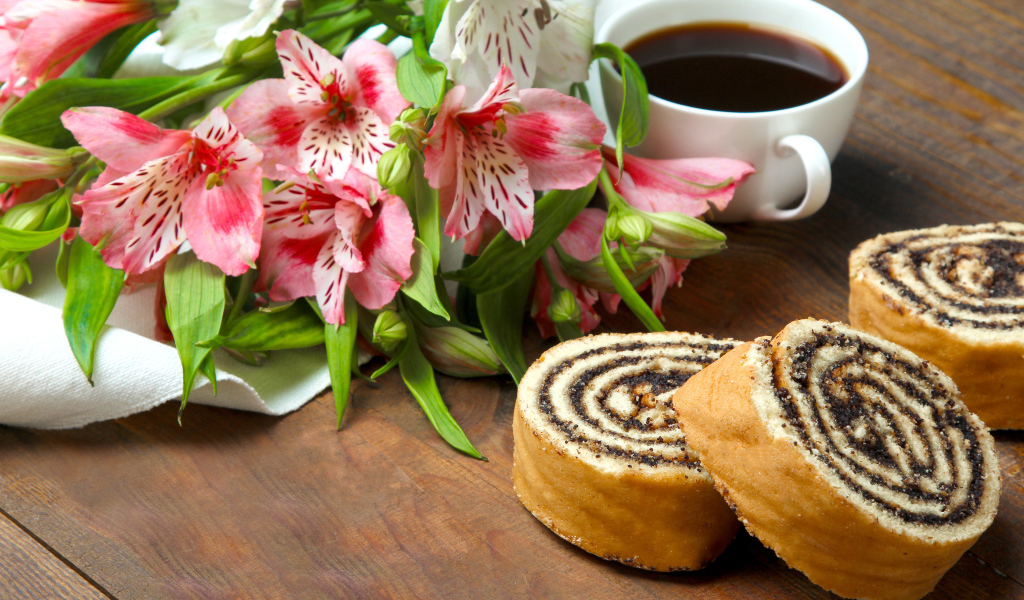 Рулет с маком на столе с цветами альстрёмерия и чашкой кофе