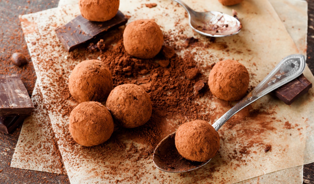 Круглые шоколадные конфеты в какао на столе с ложками