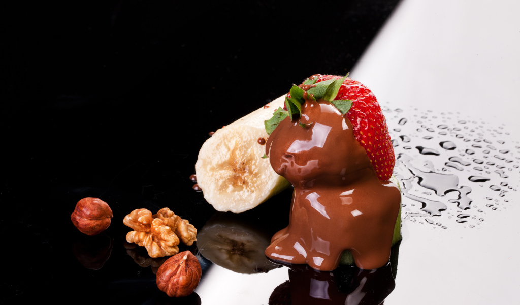 Клубника в шоколаде, банан и орехи на черной поверхности