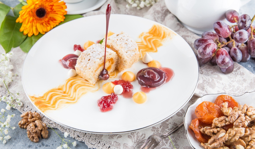 Сладкий рулет с сухофруктами и джемом на тарелке 