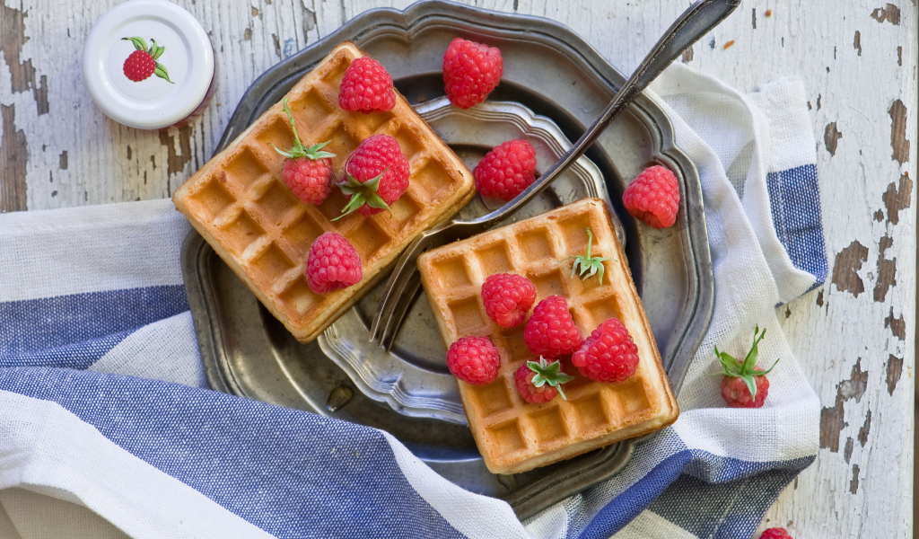 Сладкие вафли с ягодами малины на столе 