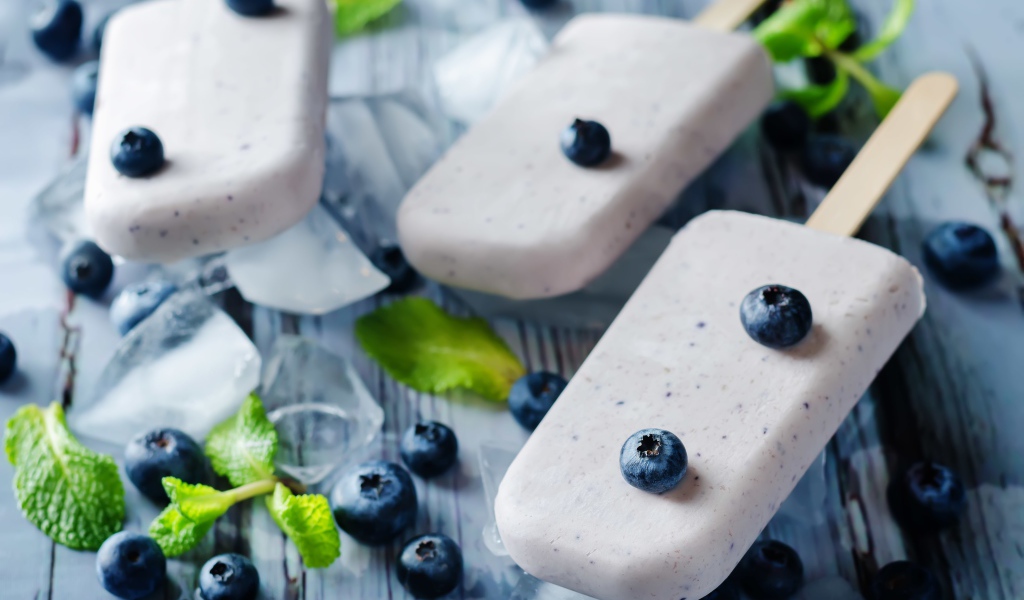 Вкусное мороженое с ягодами черники на столе с кусочками льда