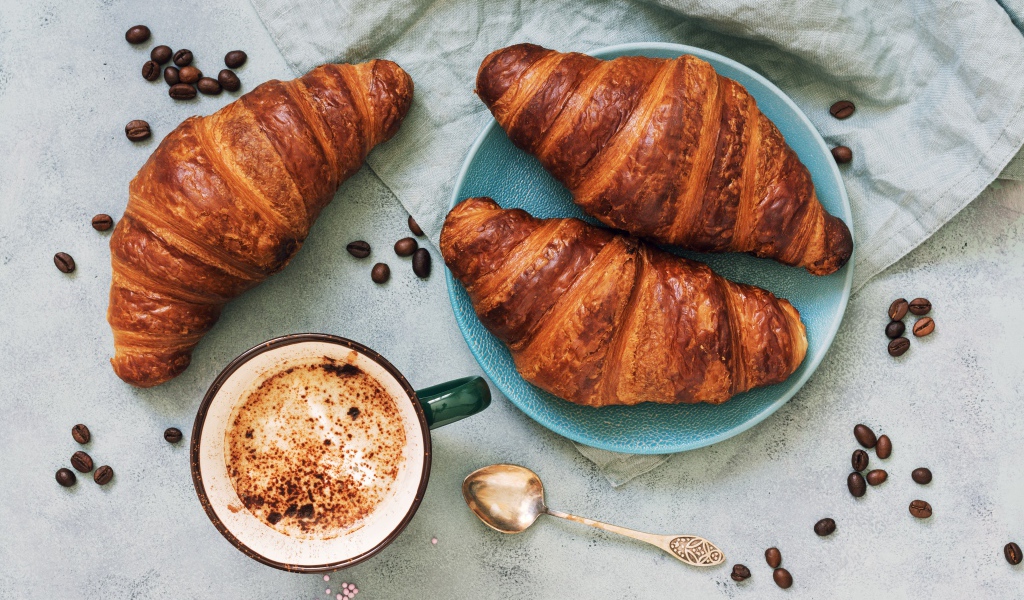 Три круассана на столе с чашкой кофе