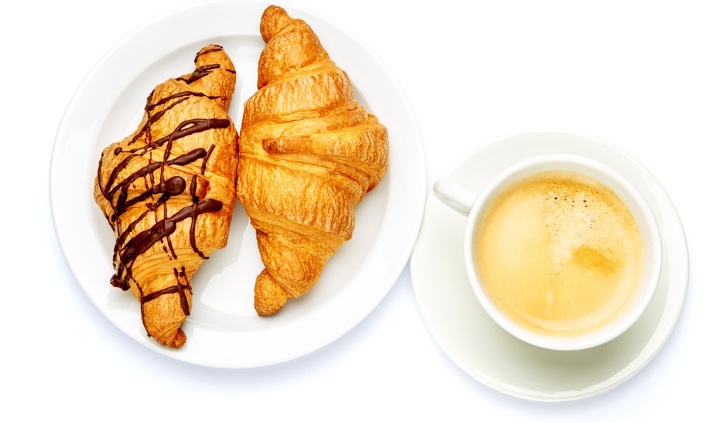 Два круассана с чашкой кофе на белом фоне