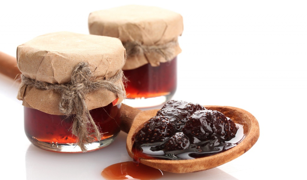 Две банки клубничного варенья на столе с ложкой 