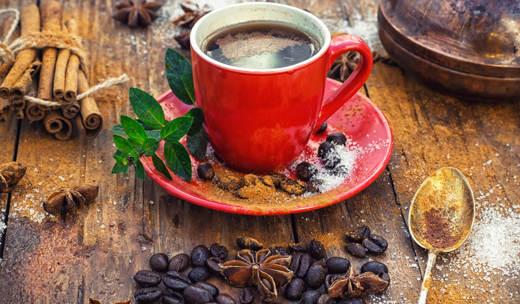Чашка кофе на столе с зернами, корицей и зернами бадьяна 