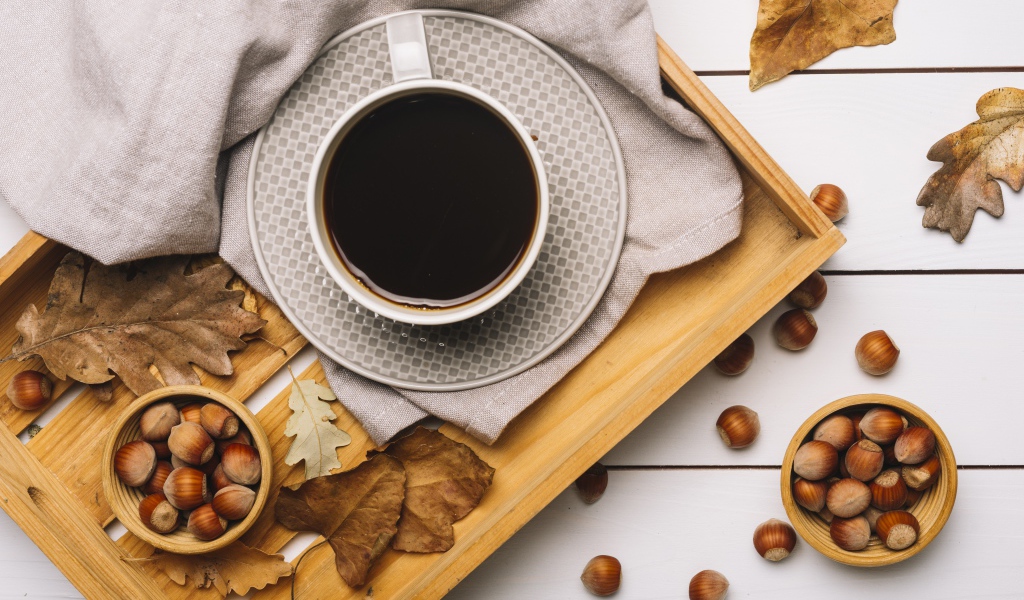 Чашка кофе на столе с лесными орехами и желтыми листьями