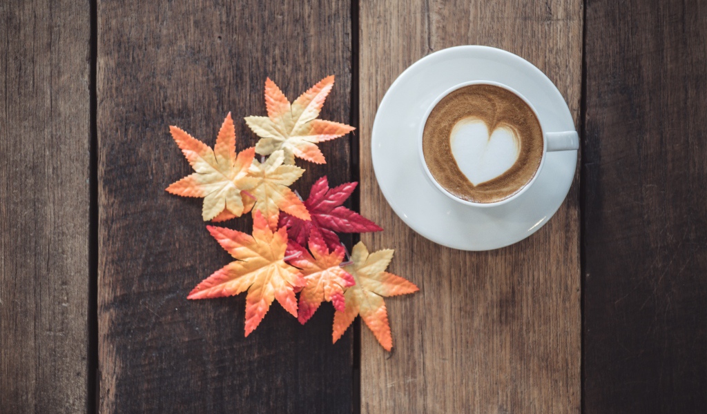 Чашка кофе на деревянном столе с желтыми листьями