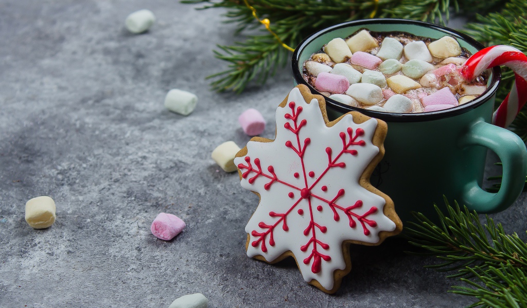 Чашка горячего напитка с кусочками маршмеллоу на столе с печеньем 