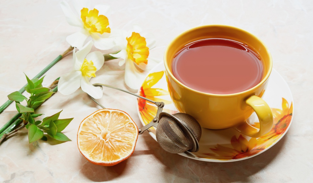 Чашка чаю на столе с лимоном и цветами нарцисса 