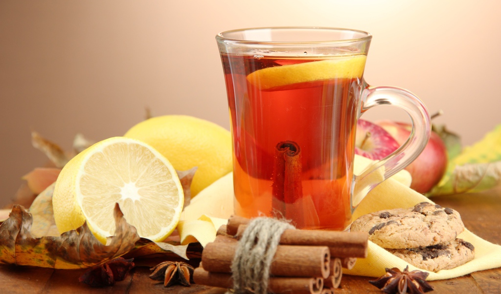 Чашка чая с лимоном и корицей на столе с лимонами