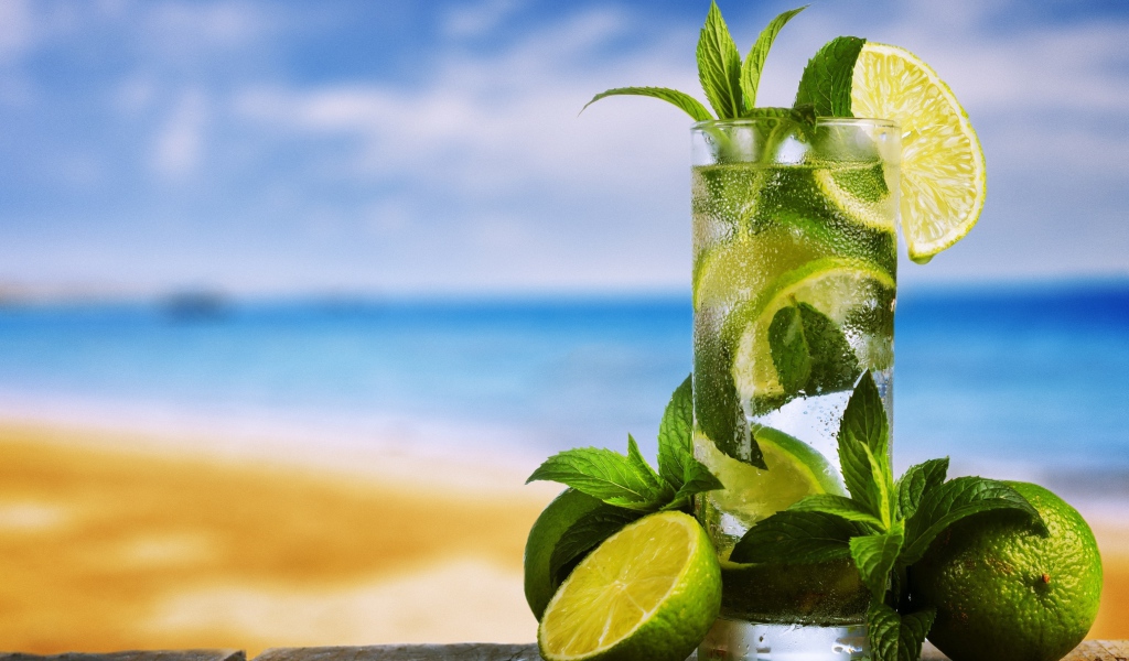 Стакан холодного мохито на столе с мятой и лаймом