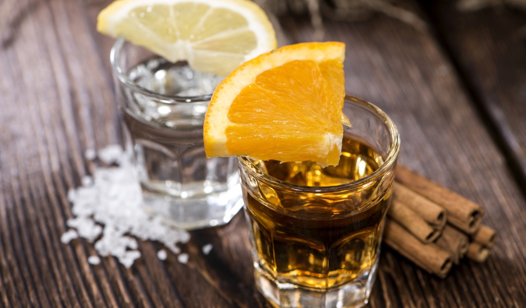Рюмка водки и рюмка виски на столе с кусочками лимона