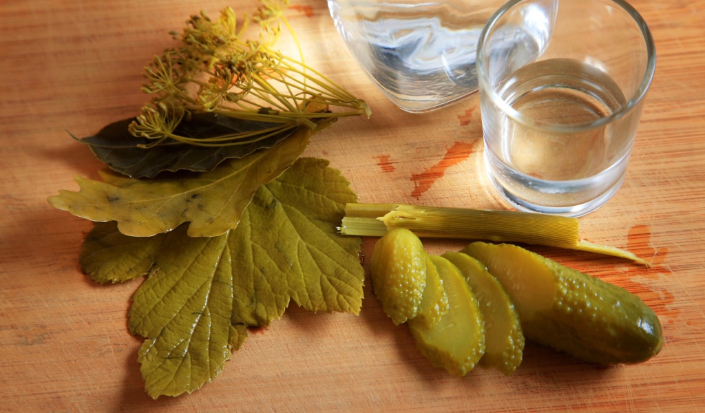 Рюмка водки на столе с соленым огурцом