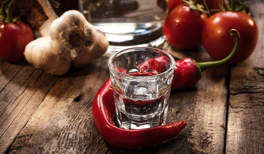 Рюмка водки на столе с красным перцем и чесноком