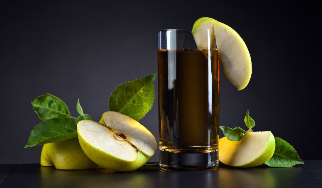 Яблочный сок в стакане на столе со свежими яблоками на сером фоне