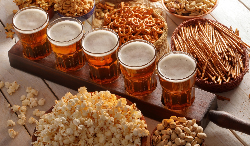 Пиво с орешками, фисташками, попкорном и печеньем на столе