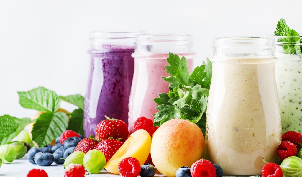 Ягодные смузи в бутылочках на столе с ягодами