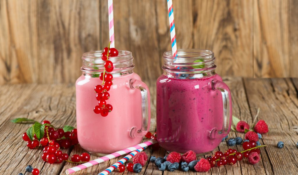 Ягодное смузи в баночках на столе со свежими ягодами малины, смородины и черники