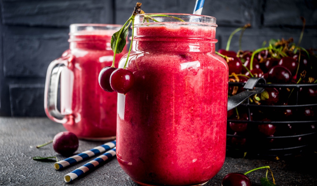 Вишневое смузи в стеклянной банке на столе с ягодами