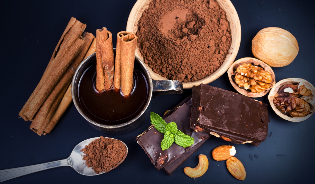 Какао с корицей, орехами и шоколадом на столе 