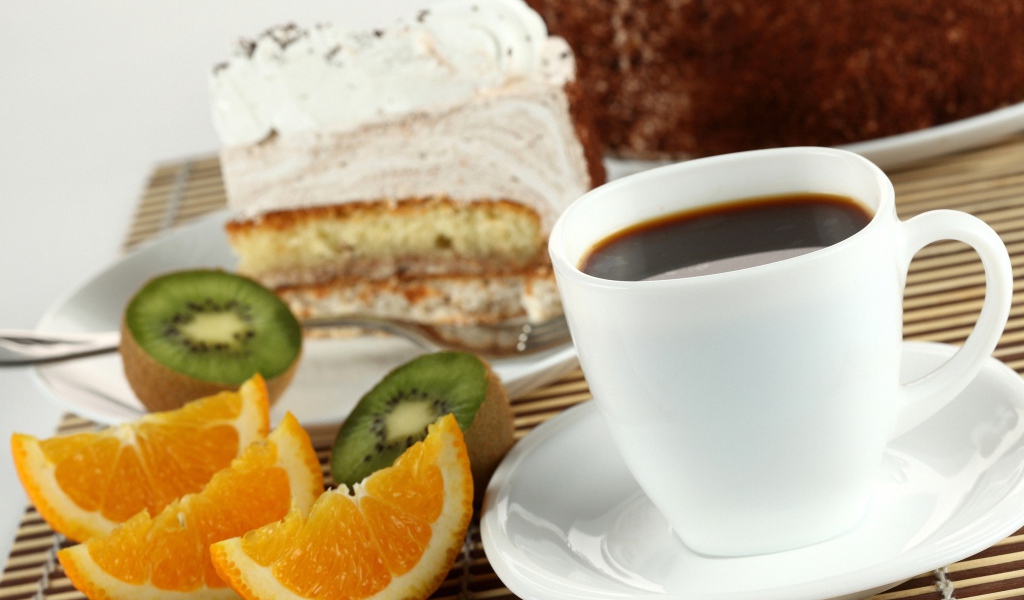 Кофе с куском торта и кусочками апельсина и киви на столе