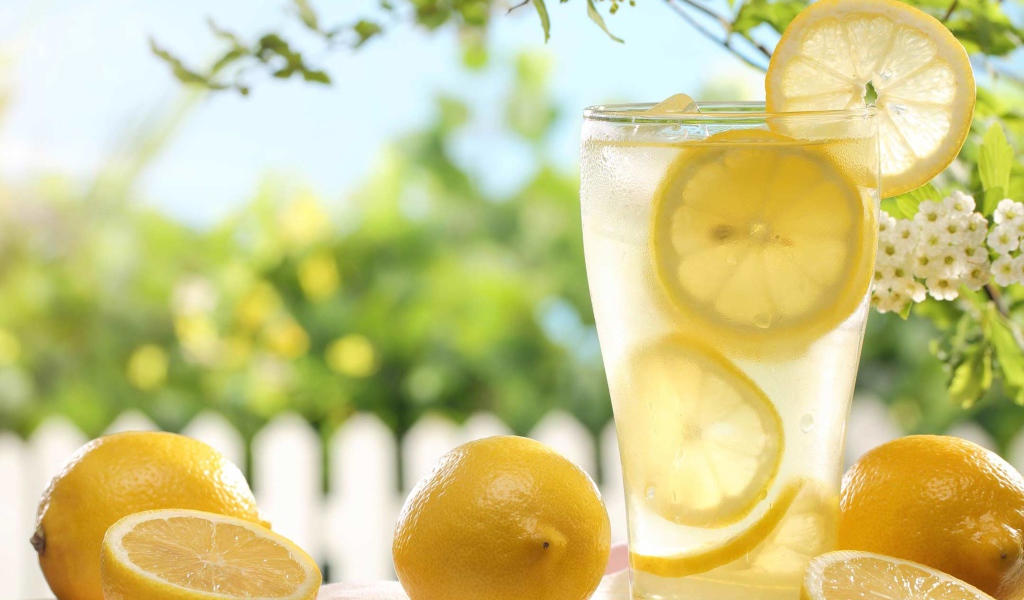Холодный лимонад в стакане с кусочками лимона