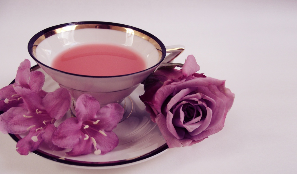 Чашка чаю на тарелке с розой и колокольчиками на сером фоне