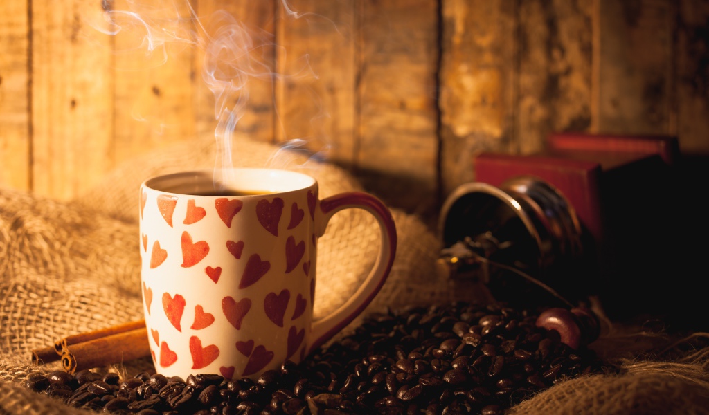 Чашка с горячим кофе на столе с кофейными зернами и корицей