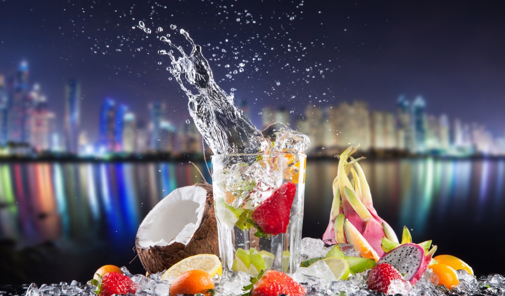 Напиток в стакане с тропическими фруктами на фоне ночного города