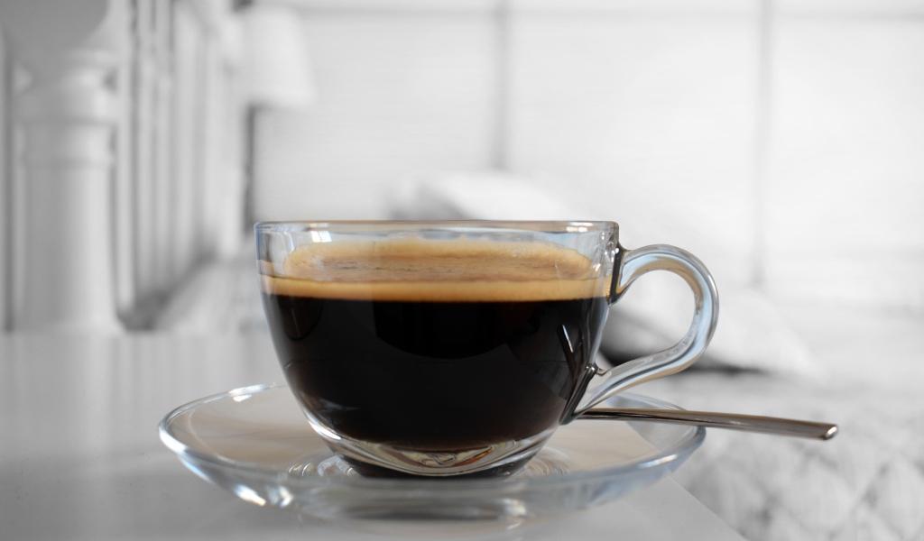Стеклянная чашка кофе на блюдце с ложкой