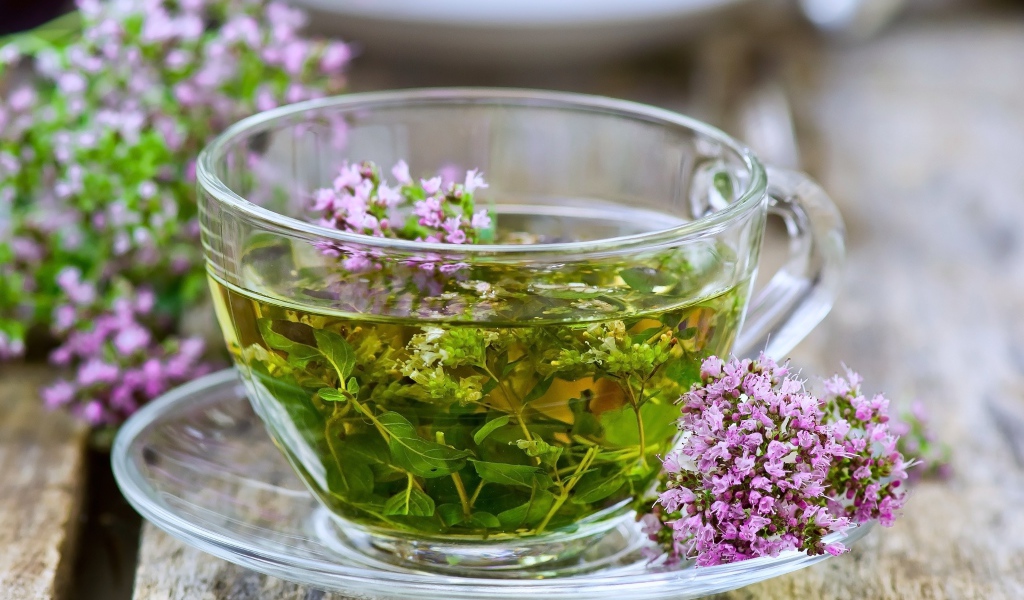 Стеклянная чашка зеленого чая с цветами чабреца