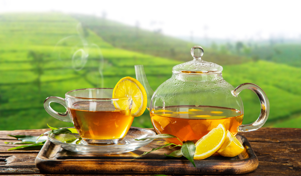 Зеленый чай с лимоном с стеклянной чашке на столе