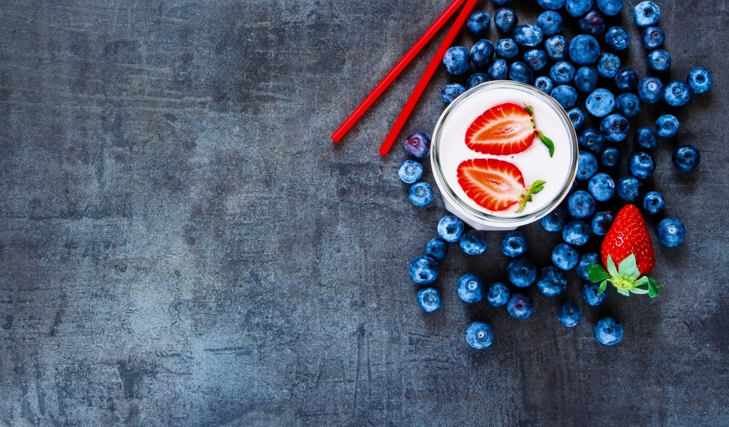 Молочный коктейль с клубникой и черникой на столе 