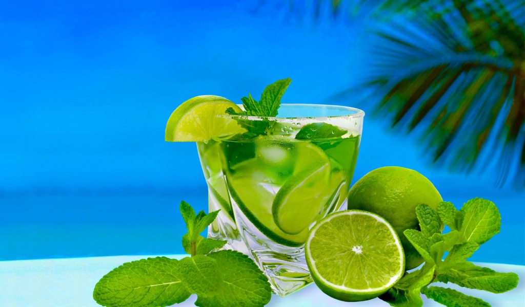 Мохито в стакане со свежей мятой и лаймом на тропическом пляже