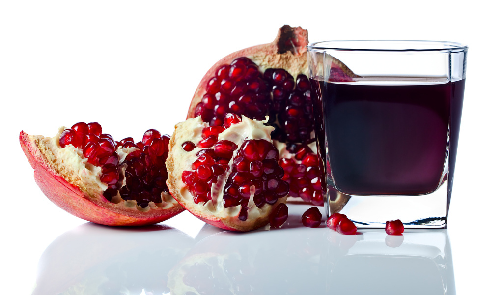 Гранатовый сок с плодом граната на белом фоне