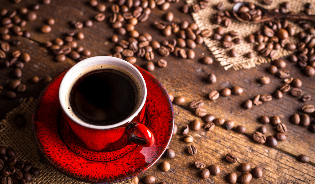 Красная чашка кофе на столе с зернами кофе